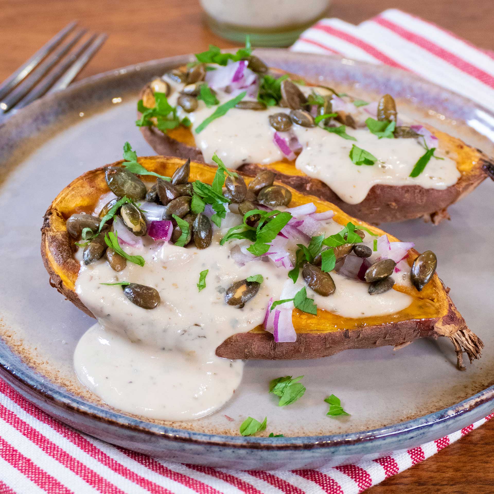 Baked sweet potato with tahini dressing and toasted pumpkin seeds