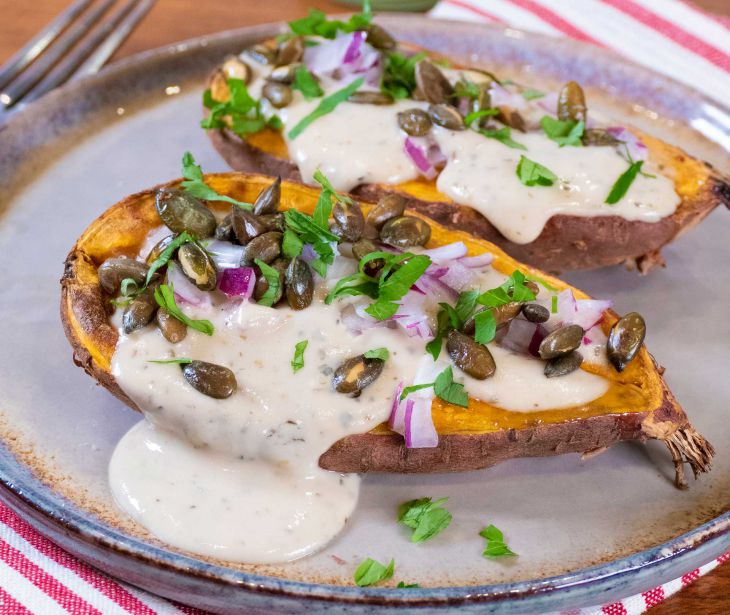 Baked sweet potato with tahini dressing and toasted pumpkin seeds